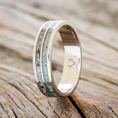 a wedding band with antler and white gold inlays is shown on a wooden surface