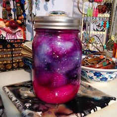 a jar filled with purple and pink liquid sitting on top of a table next to other items