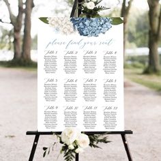 a seating sign with flowers and greenery on it