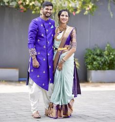 a man and woman standing next to each other in front of a building with trees