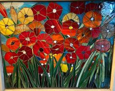 a painting with red, yellow and orange flowers painted on the glass in front of it