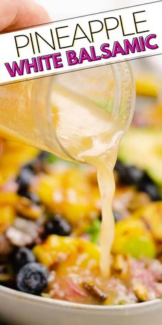 someone is pouring white balsamc into a bowl of fruit salad