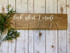 a wooden sign that says cook what i made on the side of a wall next to a potted plant