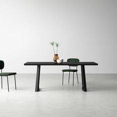 a table with two chairs and a vase on it in front of a white wall