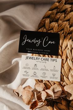 a business card sitting on top of a pile of dried leaves next to a white cloth