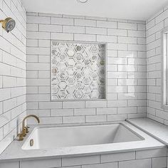 a bathroom with white tile and gold fixtures in the shower area, along with a bathtub