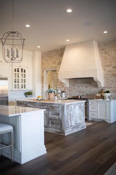 a large kitchen with an island in the middle and two lights hanging from the ceiling