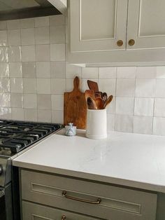 a kitchen counter with utensils in a white ceramic container next to an oven