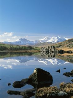 a lake surrounded by mountains with rocks in the foreground