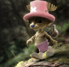 a small doll wearing a pink hat and holding a squirrel on top of a log