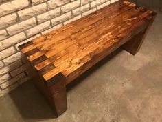 a bench made out of wood sitting in front of a brick wall and cement floor