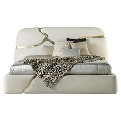 a white bed with pillows and blankets on it's headboard, in front of a white background