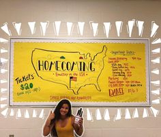 a woman standing in front of a yellow sign holding two bottles and a bottle of wine