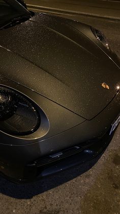 a black sports car is parked on the side of the road at night with it's hood up