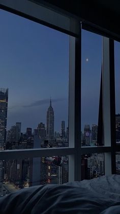 a bedroom with a view of the city from it's window sill at night