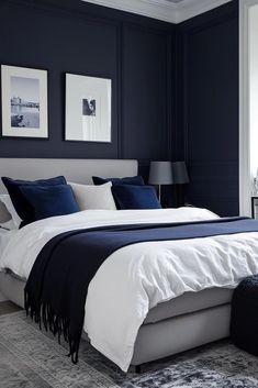 a bedroom with dark blue walls and white bedding in the corner, along with two framed pictures on the wall