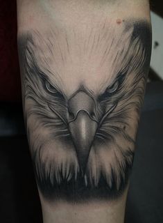 an eagle tattoo on the leg with black and grey ink, it looks like he's looking at something