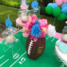 a table topped with a football cake and cupcakes on top of a green table cloth