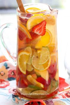 a pitcher filled with sliced fruit on top of a table