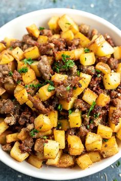 a white bowl filled with cooked potatoes and meat