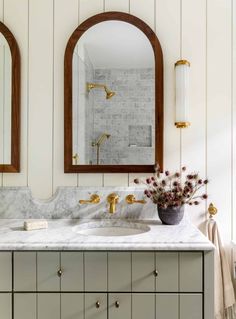 a bathroom with marble counter tops and gold faucets on the sink, along with two oval mirrors