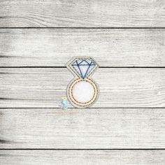 an embroidered ring with a diamond in the center on wooden planks, ready to be sewn onto