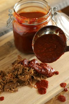 a wooden cutting board topped with lots of food next to a jar of bbq sauce