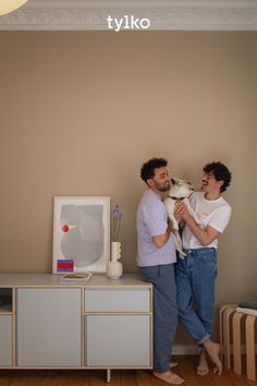 two men standing next to each other holding a dog