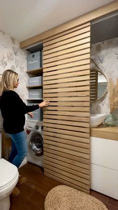 a woman standing in front of a washer next to a wall mounted dryer