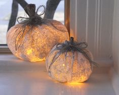 two lighted pumpkins sitting in front of a window