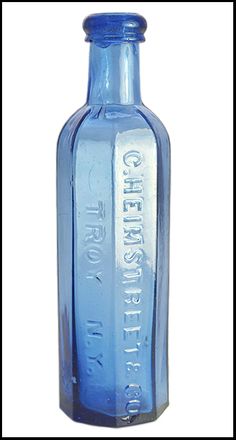 a blue glass bottle with the word chelsea on it's side, sitting in front of a white background