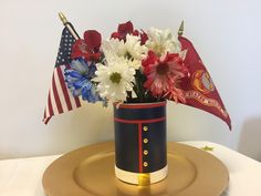 a vase with flowers in it sitting on a plate next to an american flag and two flags