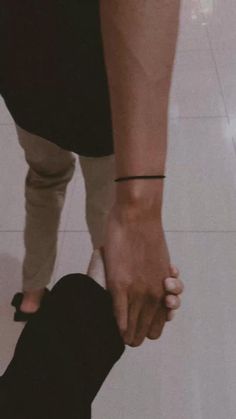 two people holding hands while standing on the floor