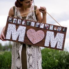 a woman holding up a wooden sign that says mom with pictures on it and hearts