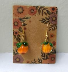 Embrace the cozy vibes with these adorable glass pumpkin earrings, featuring rich orange hues and vibrant green leaves. Perfect for adding a touch of autumn charm to any outfit, whether you're heading to a pumpkin patch, cozying up with a book, or enjoying a crisp fall day. The delicate design captures the essence of the season, making them an ideal accessory for harvest festivals, Halloween, or a casual day out. Crafted with care, these earrings are ready to bring a bit of pumpkin spice magic to your jewelry collection. Keywords: Glass pumpkin earrings, autumn jewelry, fall accessories, harvest festival, Halloween earrings, handmade earrings, pumpkin spice, orange and green earrings, seasonal jewelry, cozy vibes, autumn fashion, fall jewelry trends Handmade Jewelry For Fall, Trendy Fall Jewelry Gift, Trendy Jewelry As Fall Season Gift, Orange Earrings For Fall Season Gift, Fall Orange Earrings As Gift, Cute Nickel-free Orange Earrings, Cute Orange Nickel-free Earrings, Fall Season Gift Dangle Earrings, Cute Orange Drop Earrings