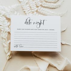 a white card with the words date night written on it next to some flowers and leaves