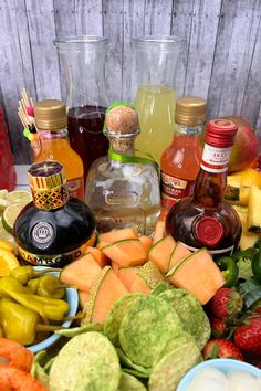 there are many different types of fruits and vegetables on the table with liquor bottles in the background