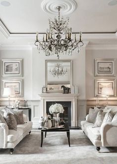 a living room filled with furniture and a chandelier hanging from the ceiling over a fire place