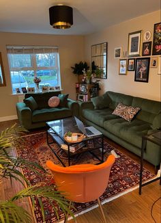 a living room with green couches and pictures on the wall above them, along with a rug