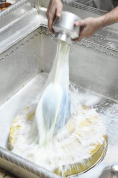 a person washing dishes in a sink with water coming out of the faucet