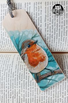 a bookmark with a bird painted on it sitting on top of an open book