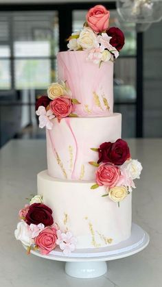 a three tiered cake with pink and red flowers