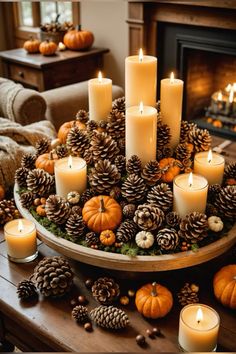 a table topped with lots of candles next to a fire place filled with pine cones and pumpkins