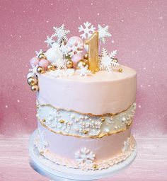 a pink and white cake decorated with snowflakes, stars and numbers on top