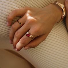 a woman's hand with two gold rings and a red stone on her finger