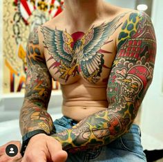 a man with lots of tattoos on his chest and arms, sitting in front of an american flag