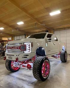 a large white truck parked in a garage with red rims on it's tires