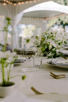 the table is set with white flowers and silverware