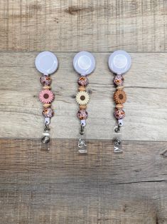 three white dishes with flower decorations hanging from them on a wooden table next to each other