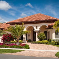 a beautiful house with palm trees and flowers in the front yard on a sunny day